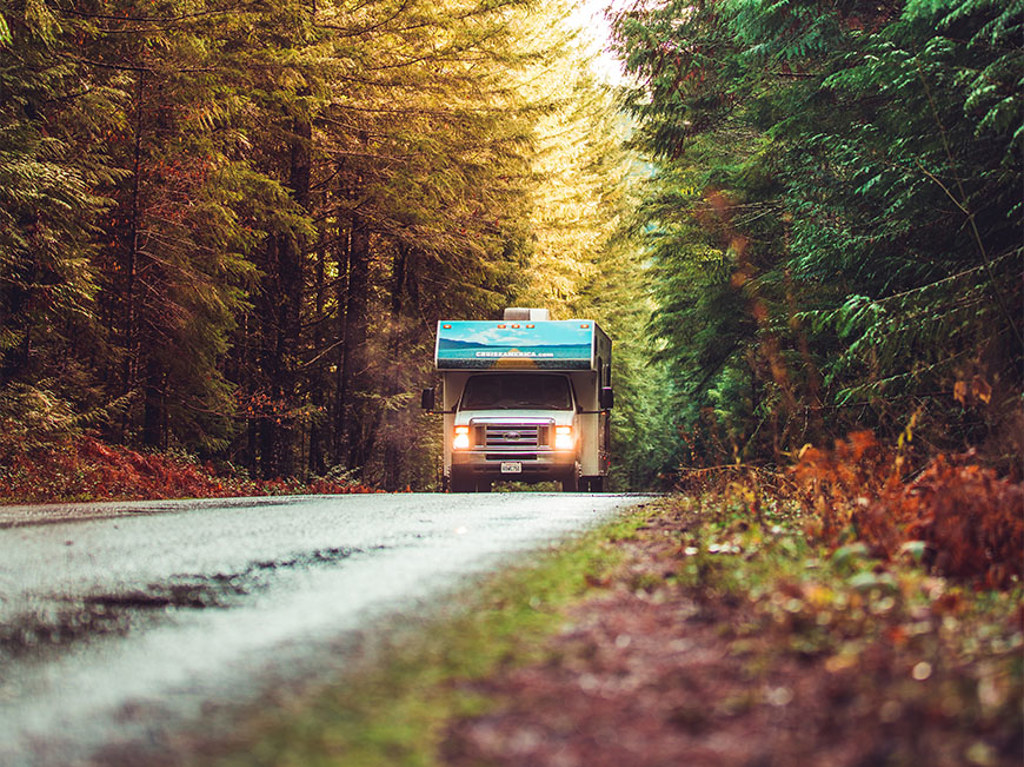 Front view of RV driving down road through woods